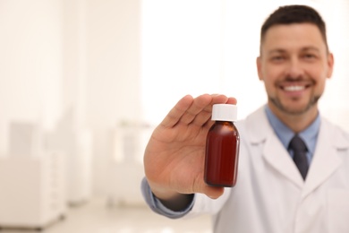 Photo of Professional pharmacist in drugstore, focus on hand with syrup. Space for text