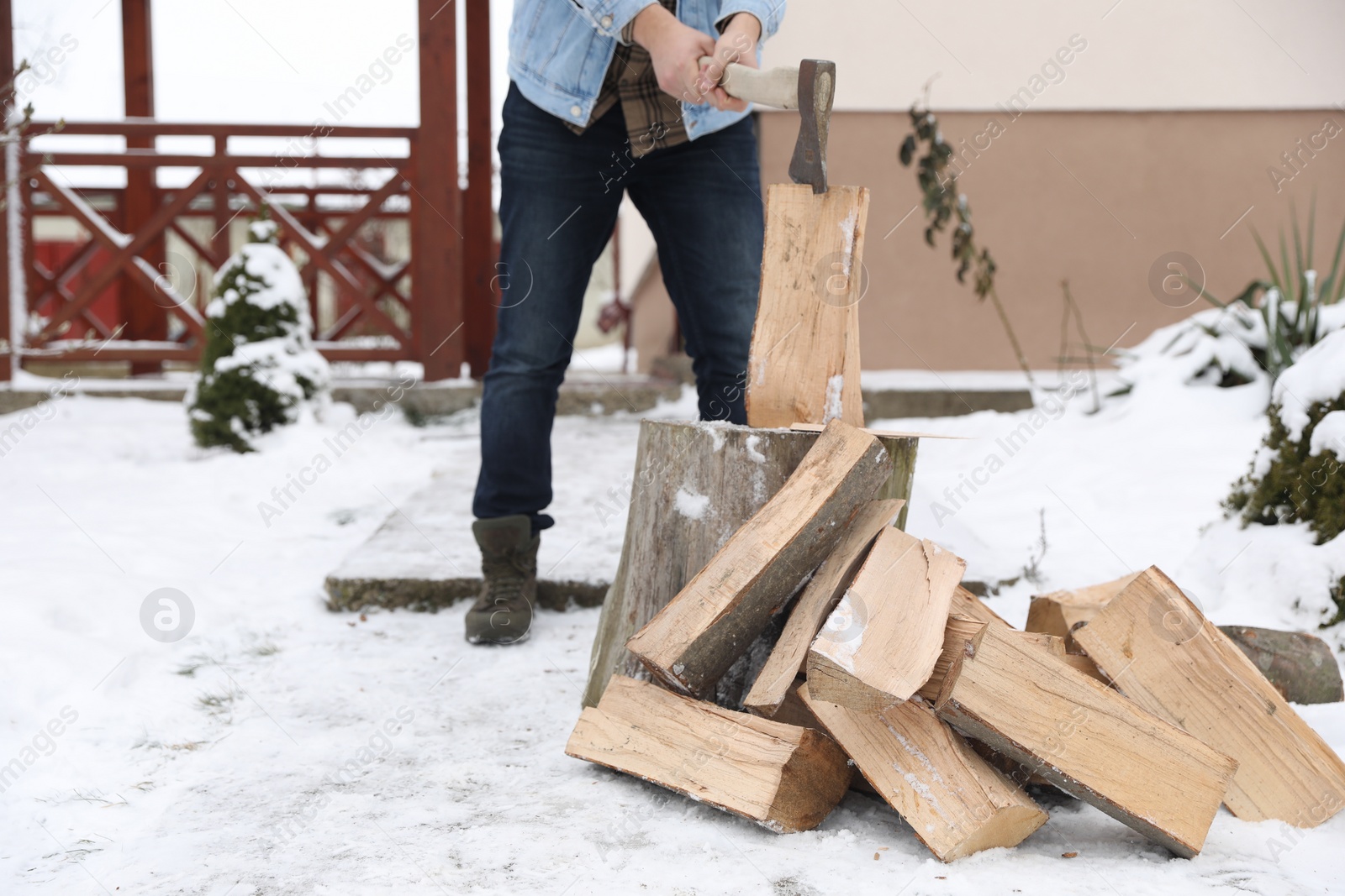 Photo of Man chopping wood with axe outdoors on winter day, closeup