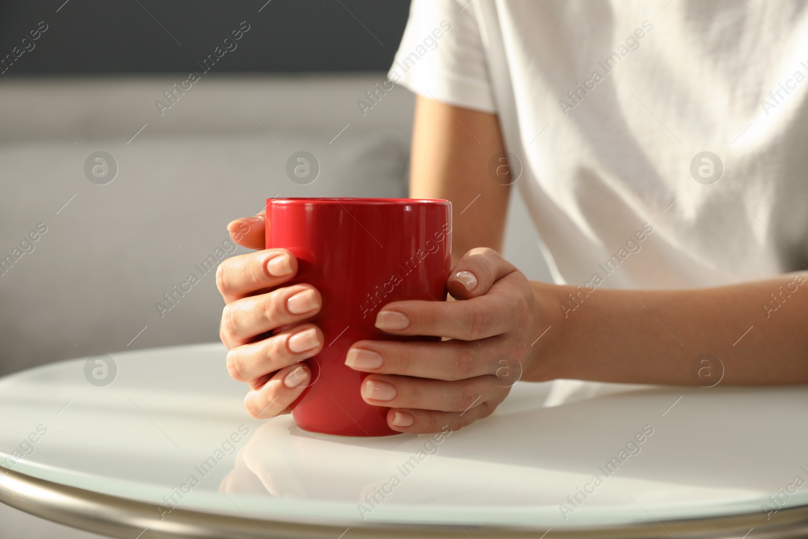 Photo of Woman with red cup at table indoors, closeup