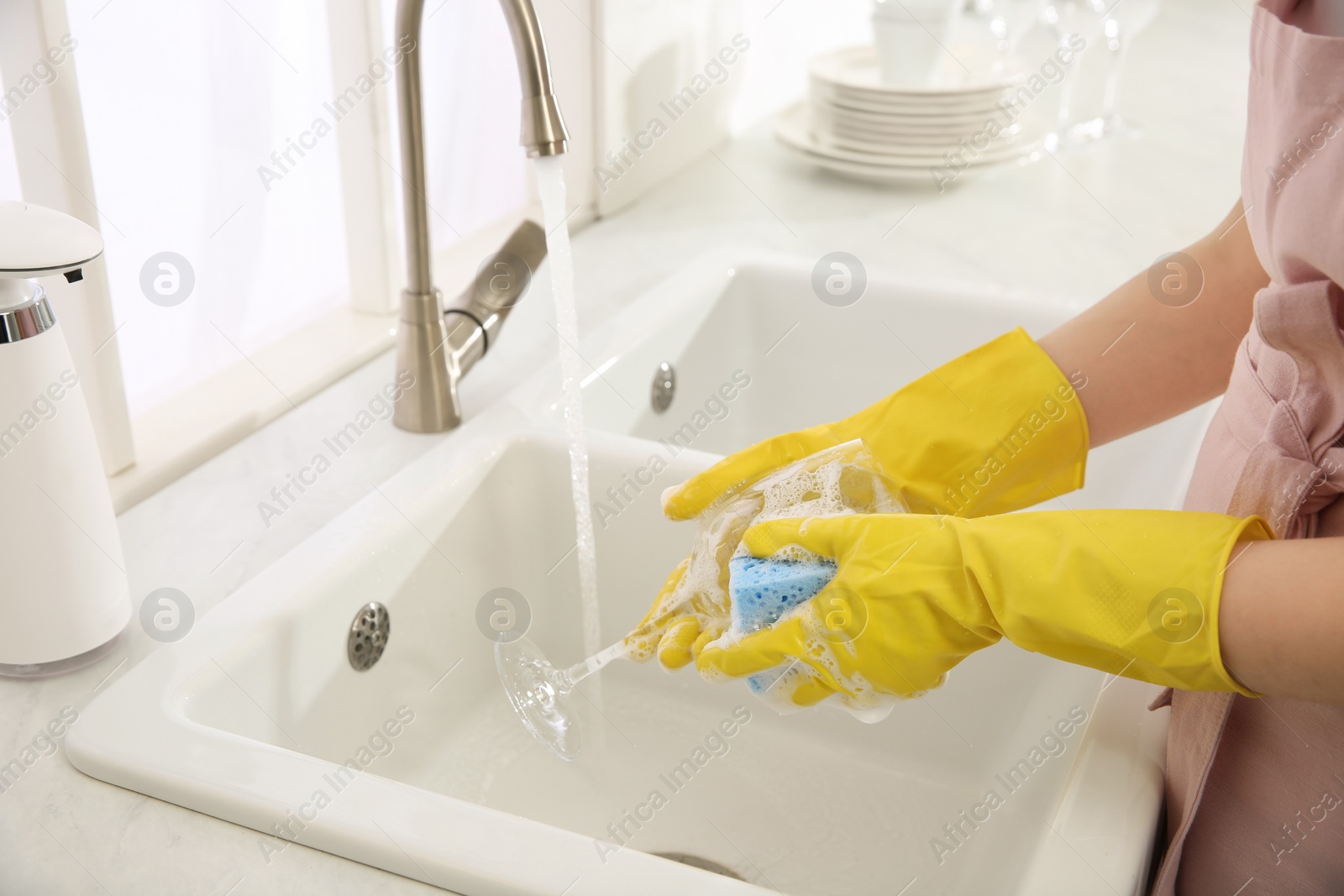 Photo of Woman washing glass in modern kitchen, closeup