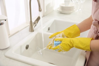 Photo of Woman washing glass in modern kitchen, closeup