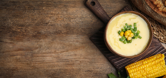 Image of Delicious corn cream soup served on wooden table, flat lay with space for text. Banner design