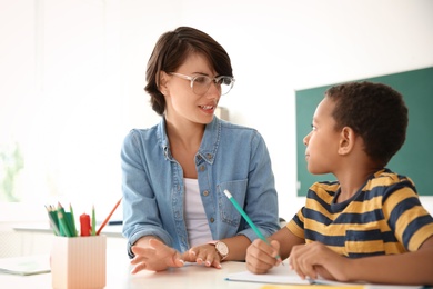 Photo of Female teacher helping child with assignment at school