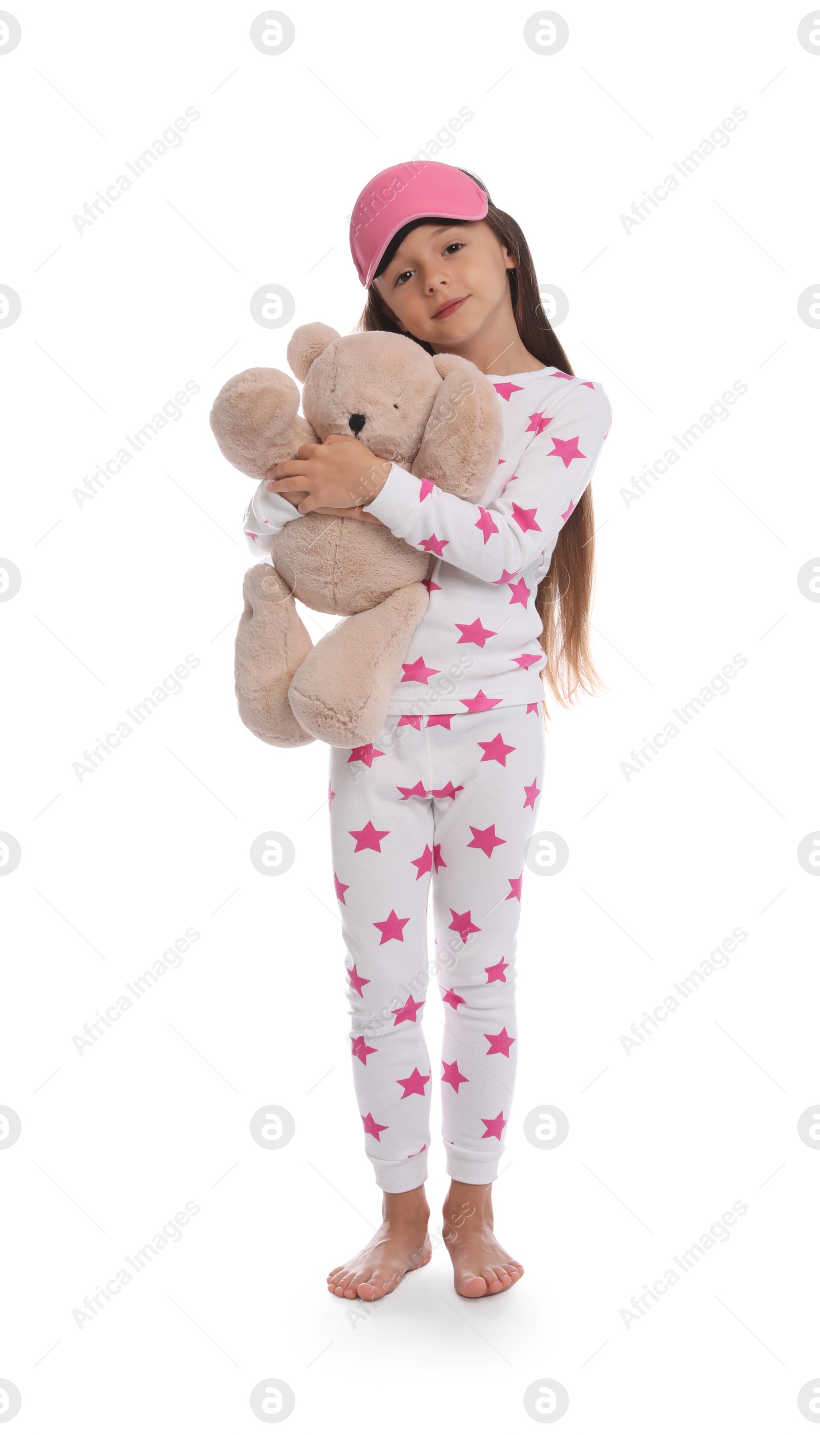 Photo of Cute girl wearing pajamas and sleeping mask with teddy bear on white background