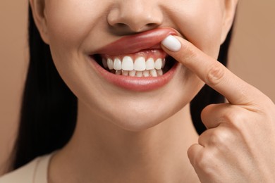 Woman showing her clean teeth on beige background, closeup