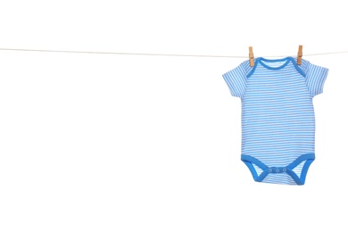 Baby onesie hanging on clothes line against white background. Laundry day