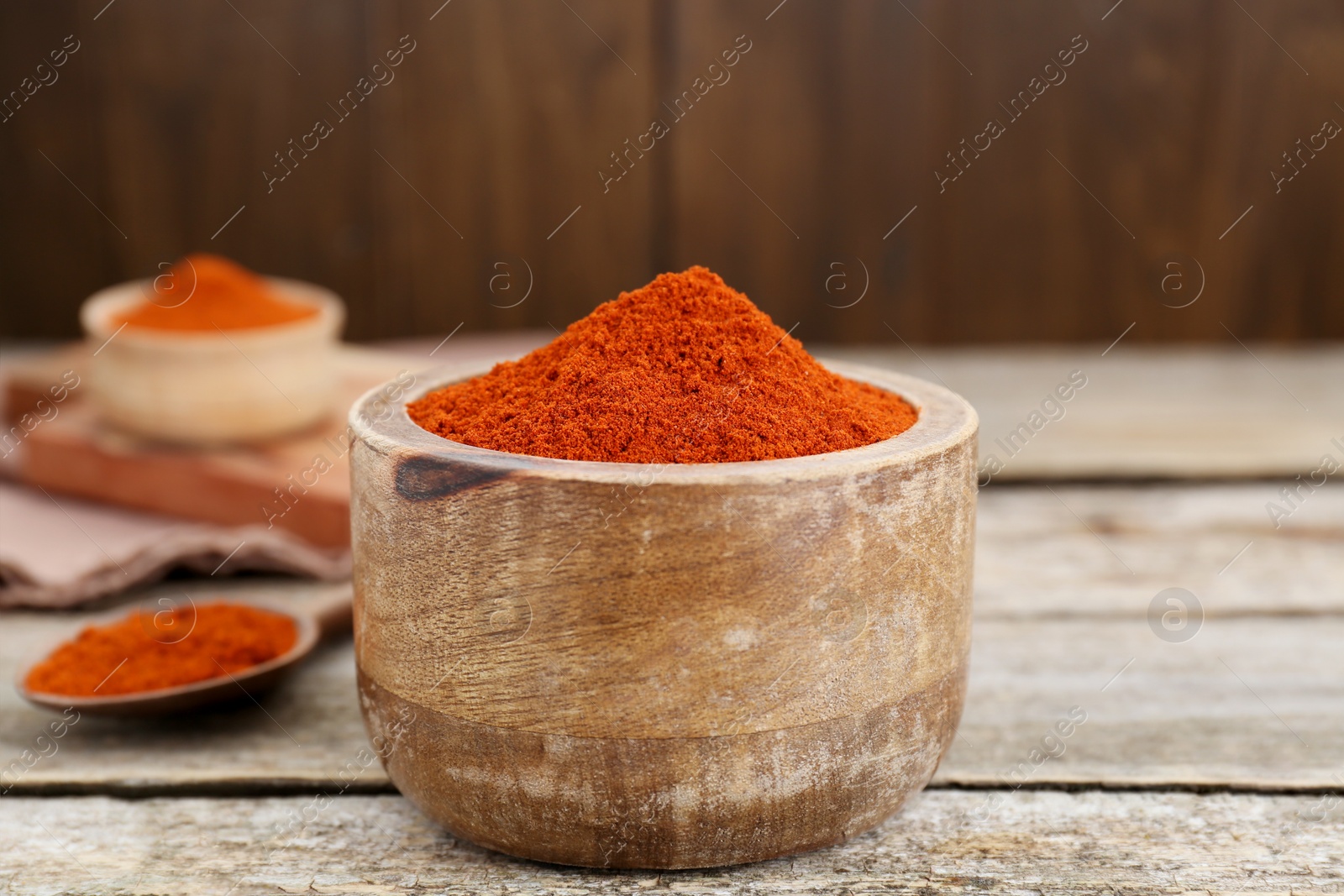 Photo of Bowl with aromatic paprika powder on old wooden table