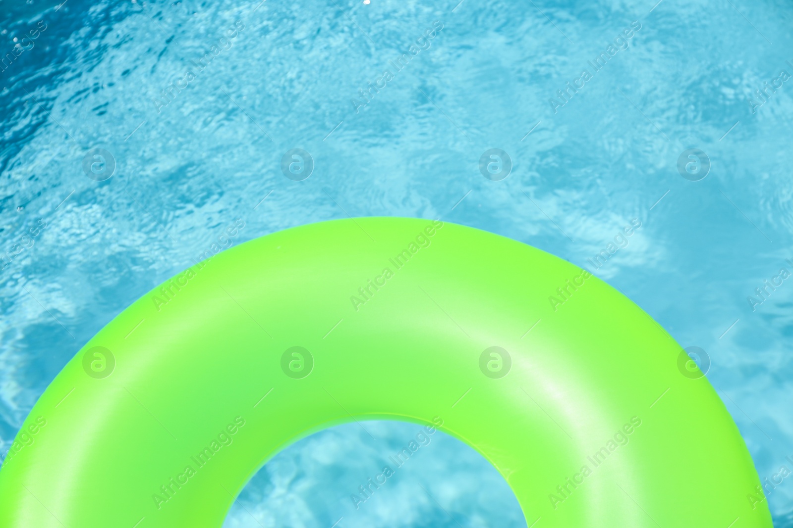 Photo of Bright inflatable ring floating in swimming pool on sunny day. Space for text