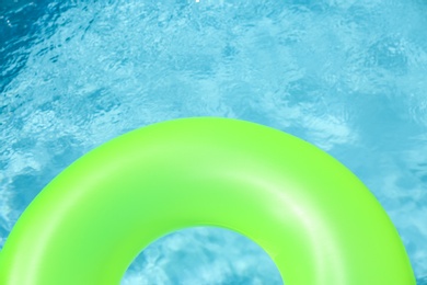 Bright inflatable ring floating in swimming pool on sunny day. Space for text