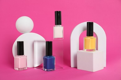 Photo of Stylish presentation of bright nail polishes in bottles on magenta background