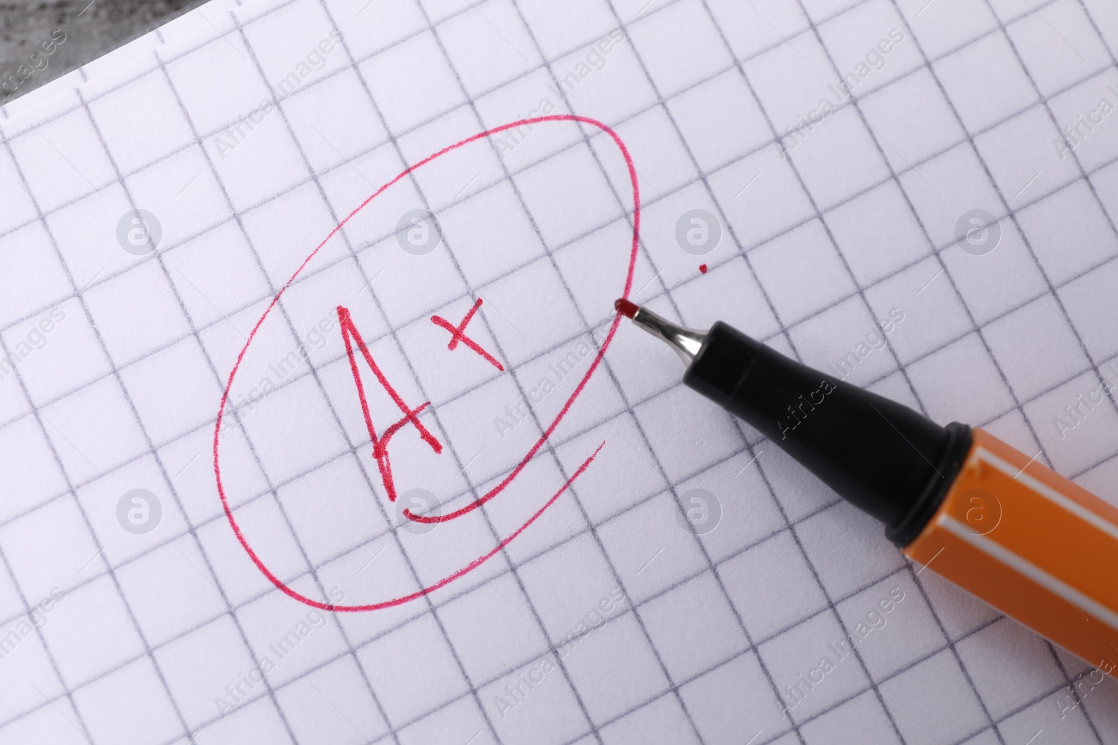 Photo of School grade. Red letter A with plus symbol on notebook paper and pen, top view