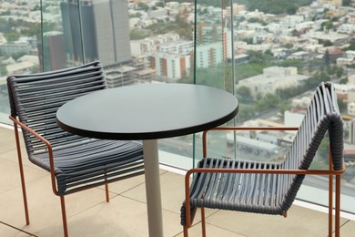 Photo of Coffee table and chairs against picturesque landscape of city in cafe