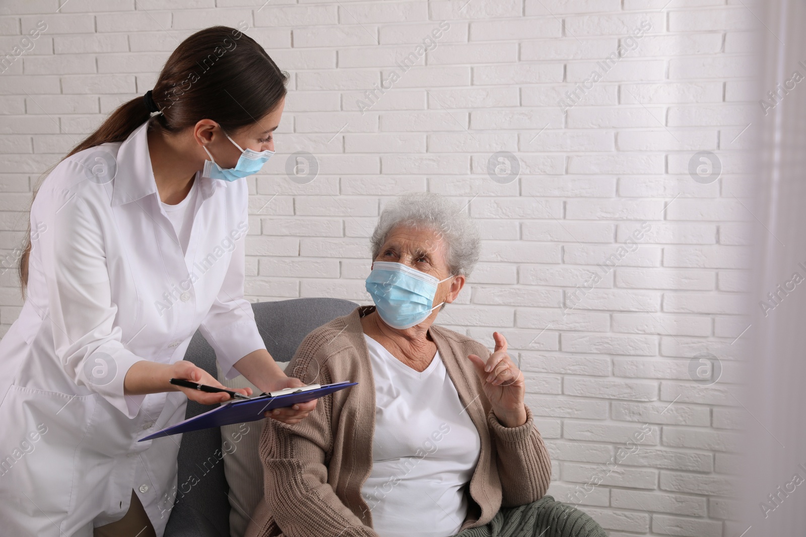 Photo of Doctor examining senior woman with protective mask at nursing home