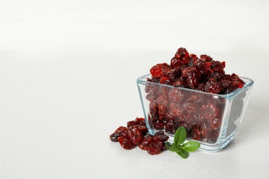 Photo of Tasty dried cranberries and leaves on white table. Space for text