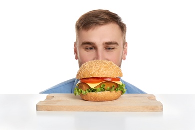 Young man and tasty burger on white background