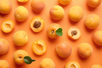 Photo of Delicious ripe sweet apricots on orange background, flat lay