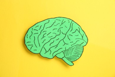 Photo of Paper cutout of human brain on yellow background, top view