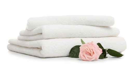 Stack of clean folded towels with flower on white background