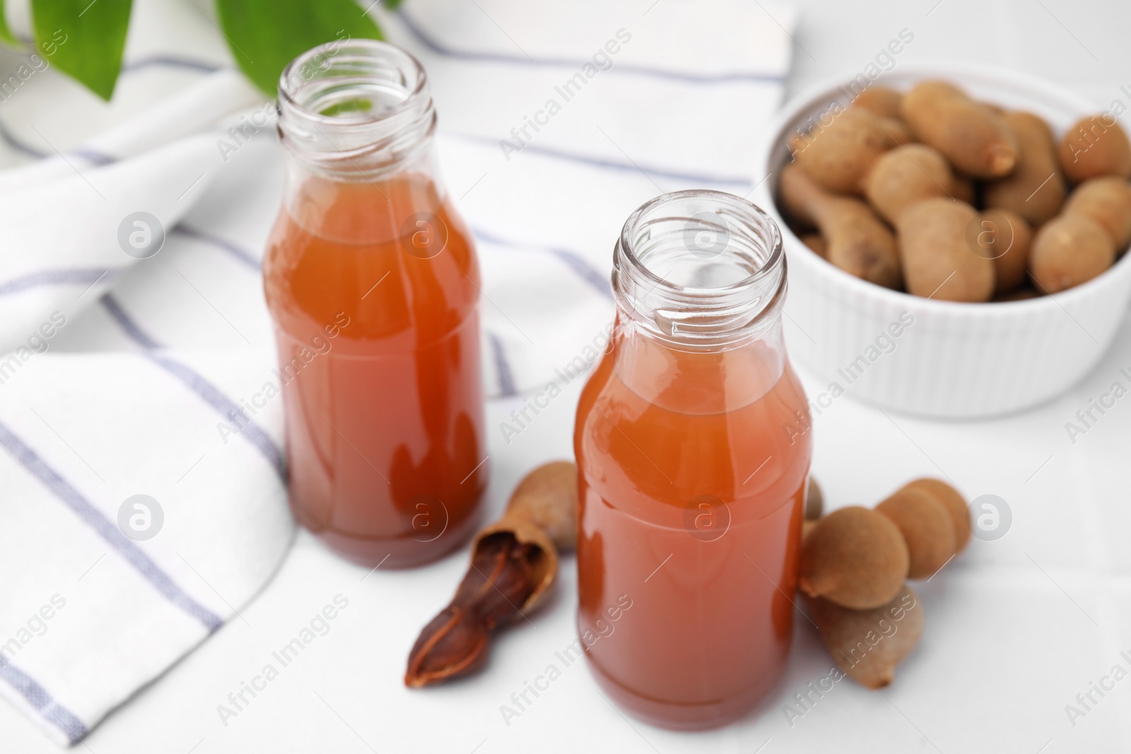 Photo of Tamarind juice and fresh fruits on white table, closeup