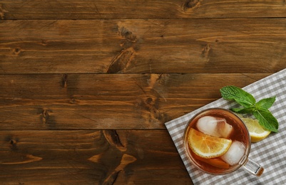 Photo of Cup of delicious iced tea on wooden table, top view. Space for text