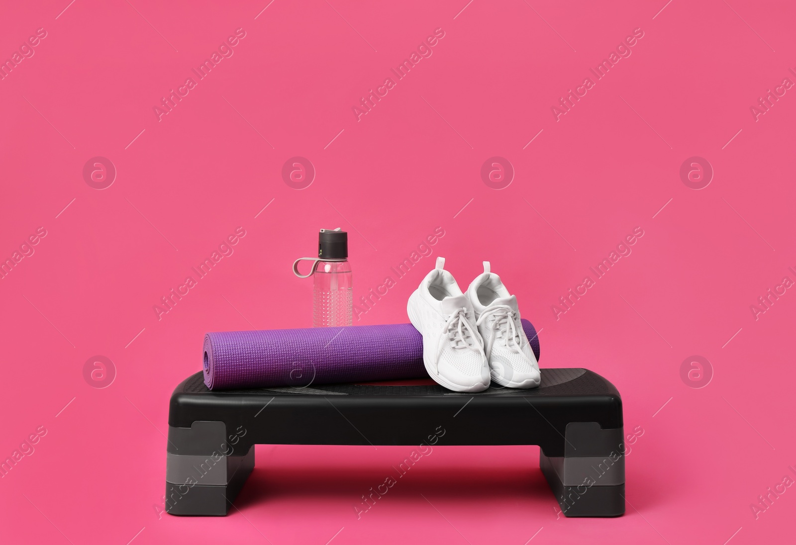 Photo of Step platform, mat, shoes and bottle of water on pink background. Sports equipment