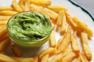 Photo of Plate with french fries and avocado dip on black table, closeup