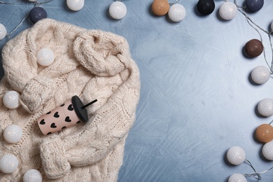 Photo of Flat lay composition with warm sweater and lights on color background. Space for text