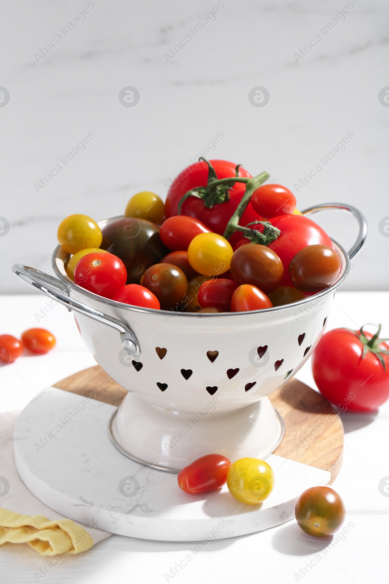 Photo of Metal colander with fresh tomatoes on white wooden table