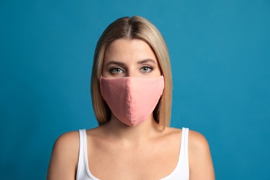 Young woman in protective face mask on blue background