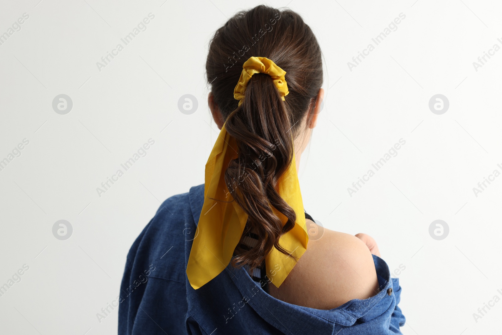 Photo of Young woman with stylish yellow bandana on light background, back view