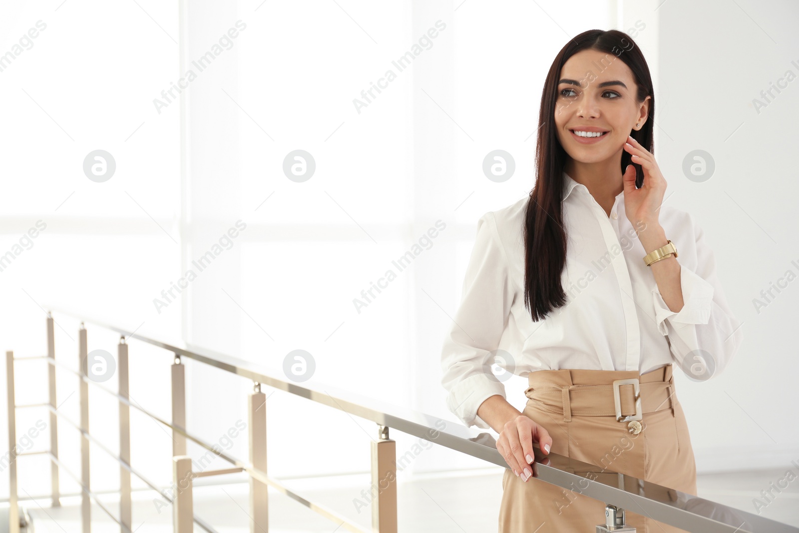 Photo of Happy young businesswoman leaning on railing in office. Space for text