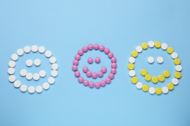Photo of Happy faces made of antidepressant pills on light blue background, flat lay