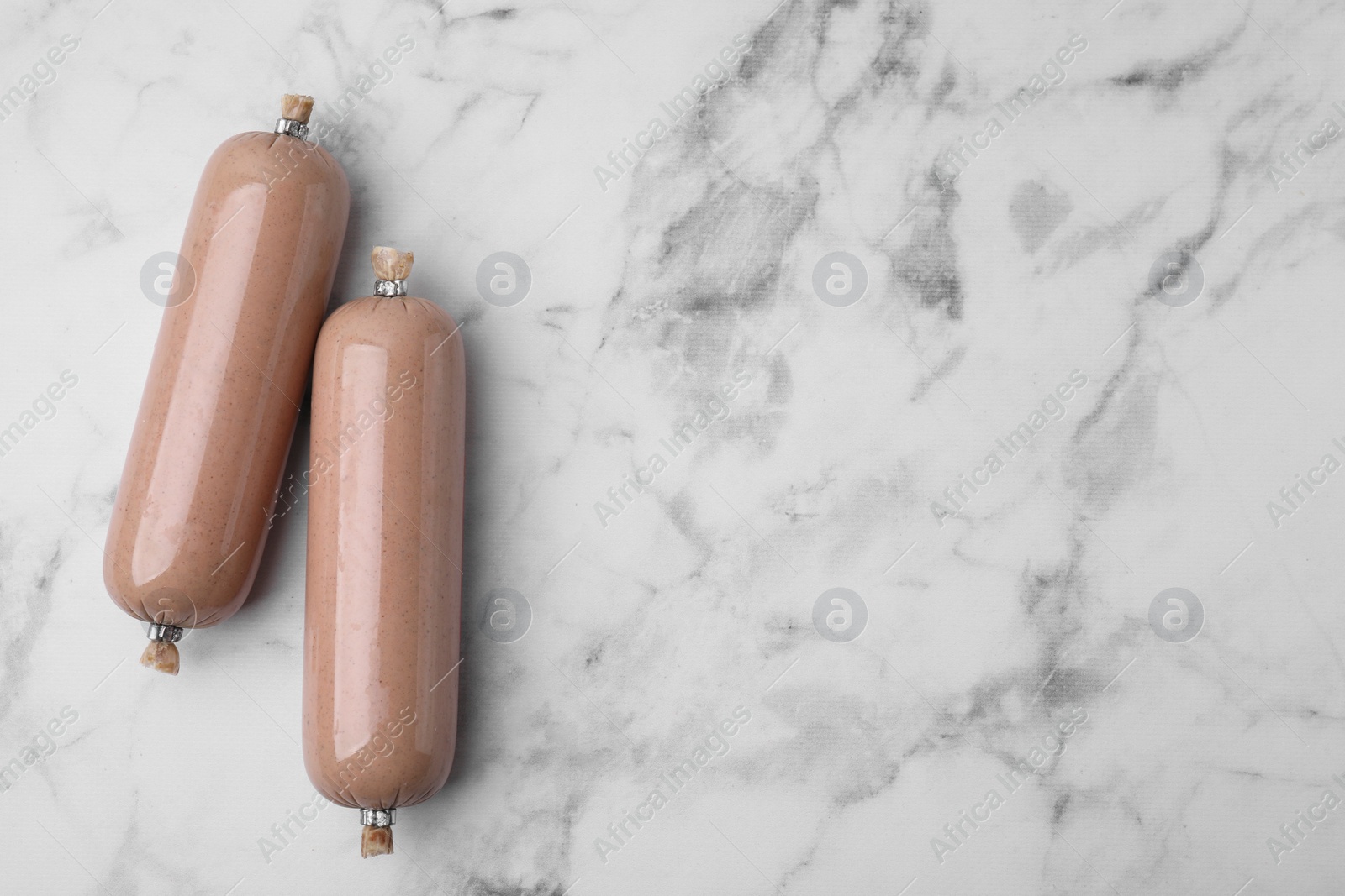 Photo of Delicious liver sausages on white marble table, flat lay. Space for text