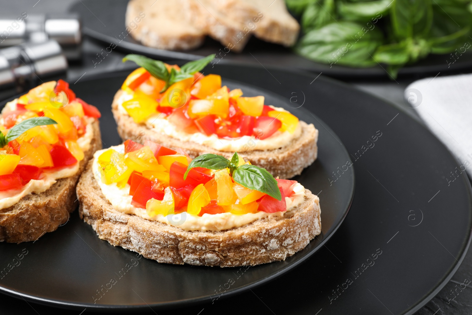 Photo of Tasty fresh tomato bruschettas on black plate