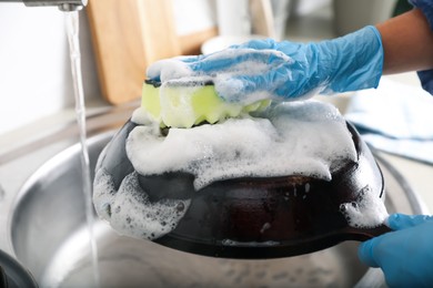 Photo of Woman washing dirty frying pan in sink indoors, closeup