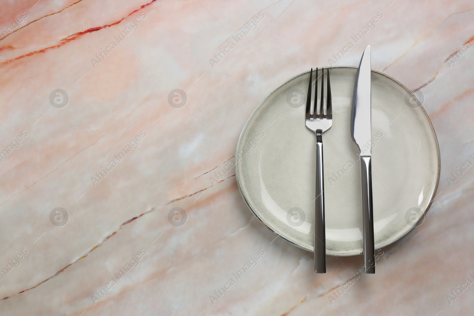 Photo of Clean plate and cutlery on beige marble table, top view. Space for text