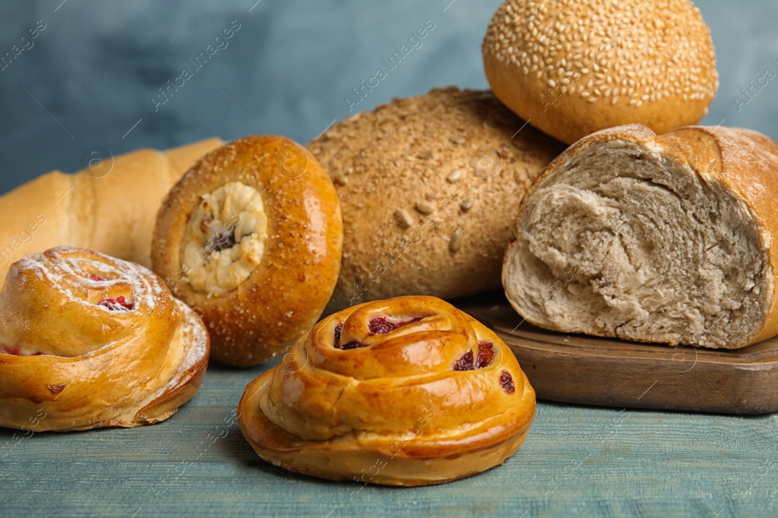 Photo of Fresh breads and pastries on blue wooden table