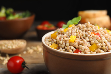 Photo of Tasty buckwheat porridge with vegetables in bowl, closeup