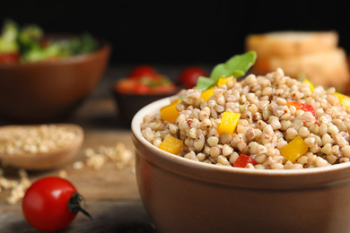 Tasty buckwheat porridge with vegetables in bowl, closeup