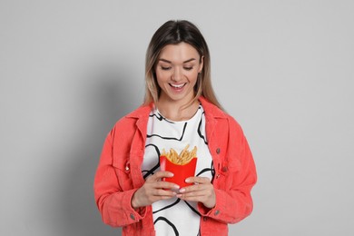 Photo of Young woman with French fries on grey background