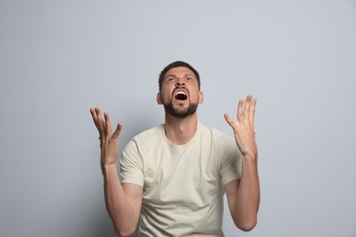 Photo of Aggressive man shouting on grey background. Hate concept