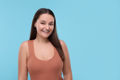 Smiling woman with dental braces on light blue background. Space for text