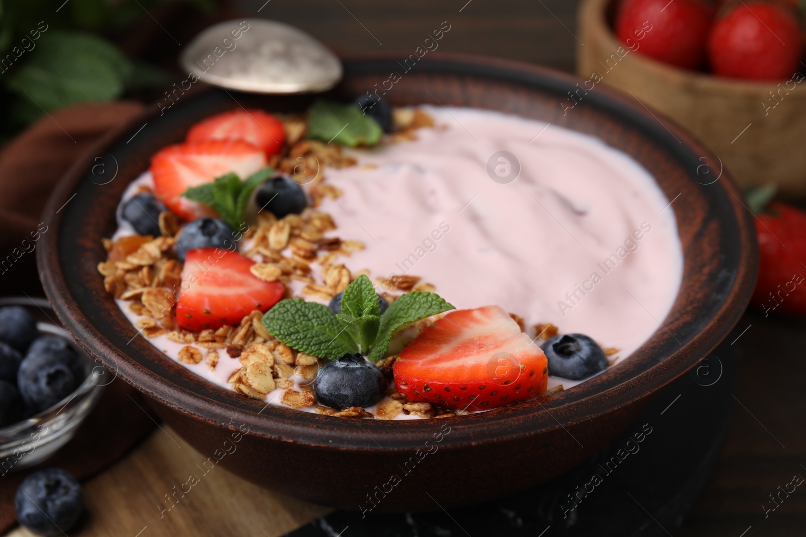 Photo of Bowl with yogurt, berries and granola on wooden table, closeup