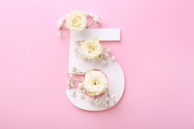 Photo of Paper number 5 and beautiful flowers on pink background, top view