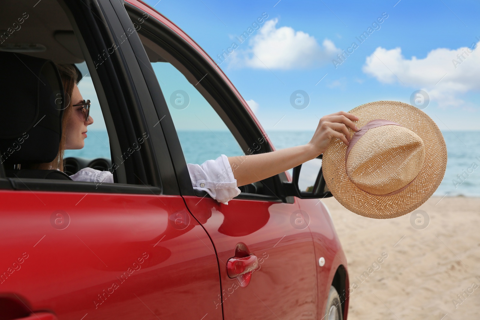 Photo of Woman waving from car on beach. Summer vacation trip