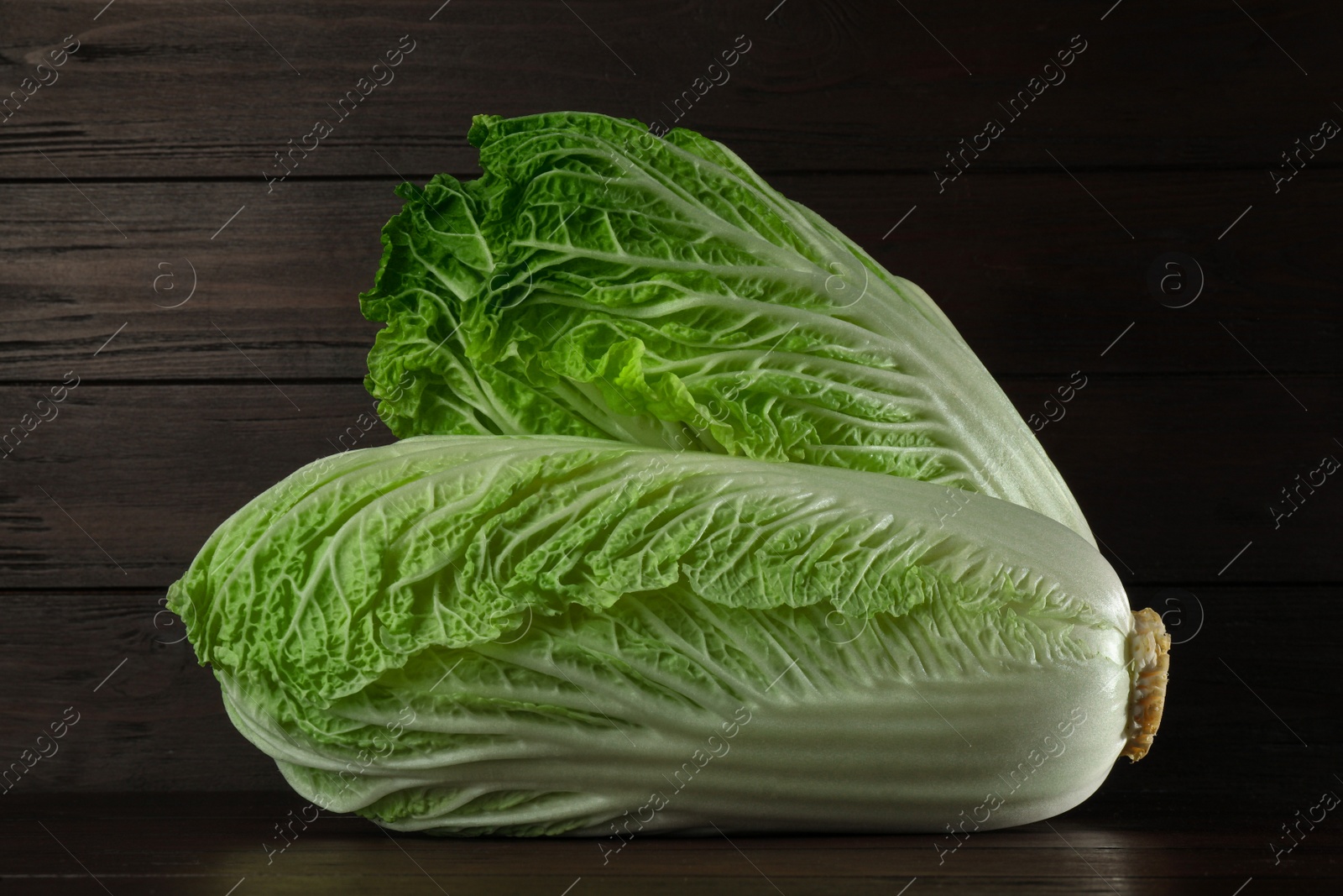 Photo of Fresh ripe Chinese cabbages on table against wooden background
