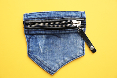 Photo of Stylish jeans pocket with zipper on yellow background, top view
