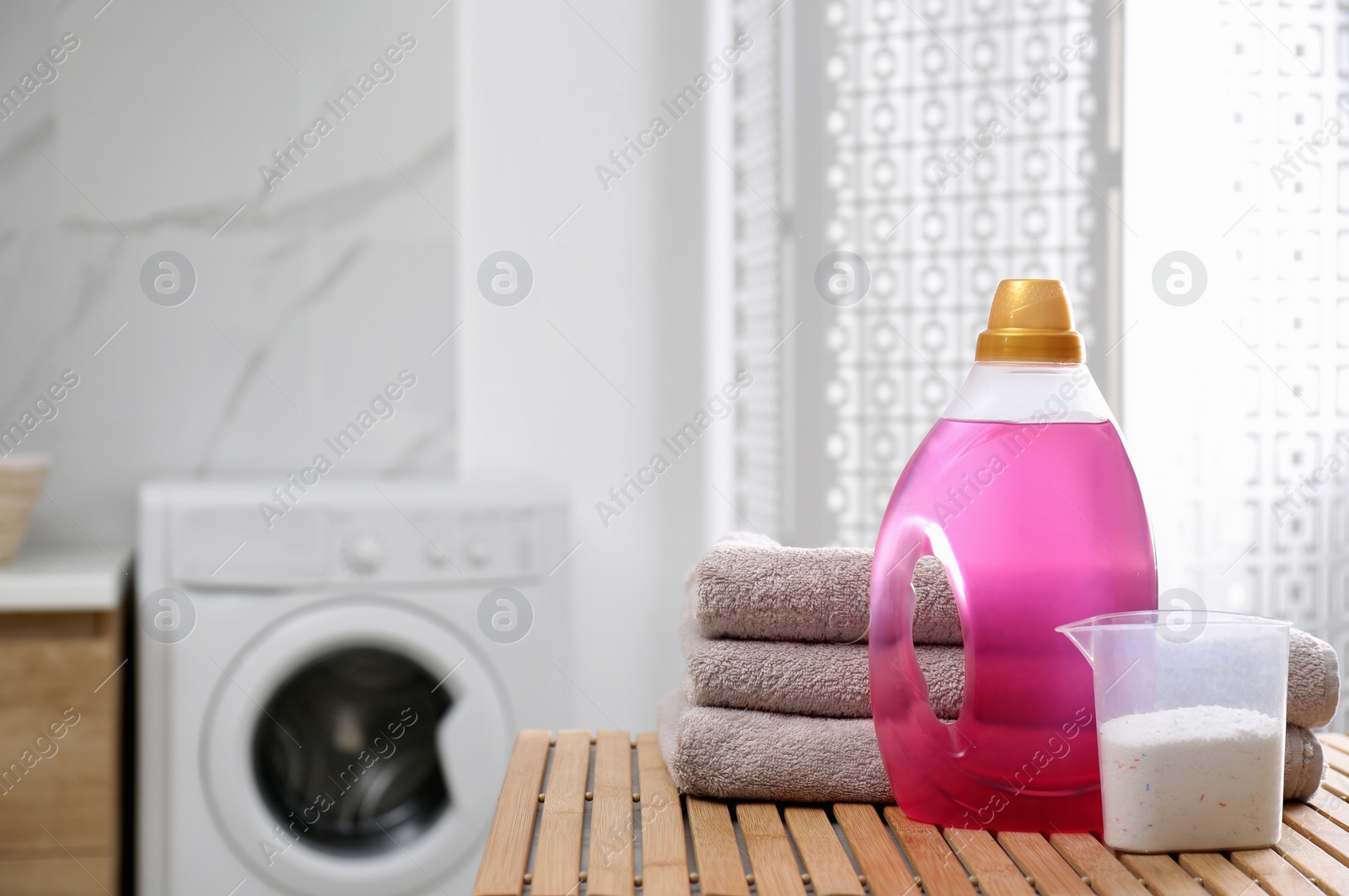 Photo of Stack of folded towels and detergents on wooden table in bathroom, space for text