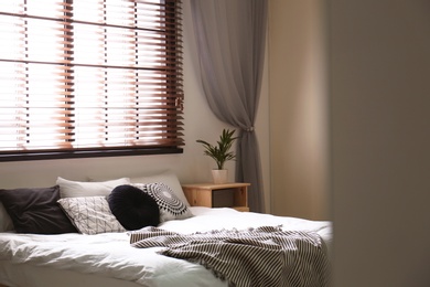 Modern room interior with comfortable double bed and window blinds