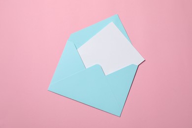 Letter envelope with card on pink background, top view